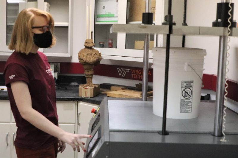 Image 1. Rosa Williams conducting compression testing of a plastic pail on the Lansmont Squeezer.